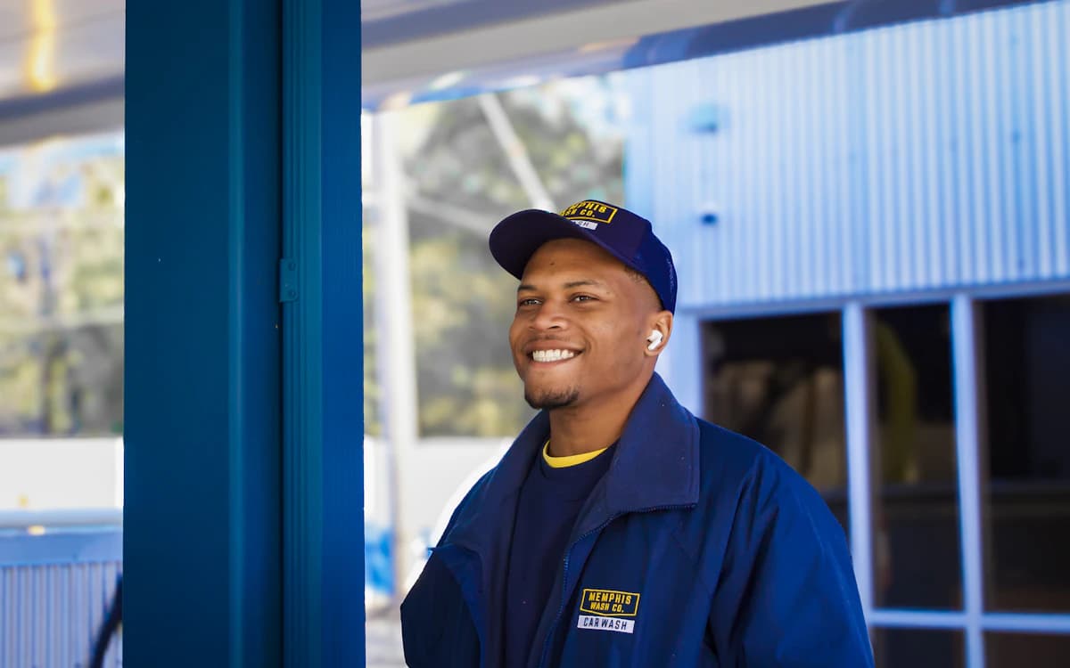 A smiling field service technician in a blue work uniform arriving at a site
