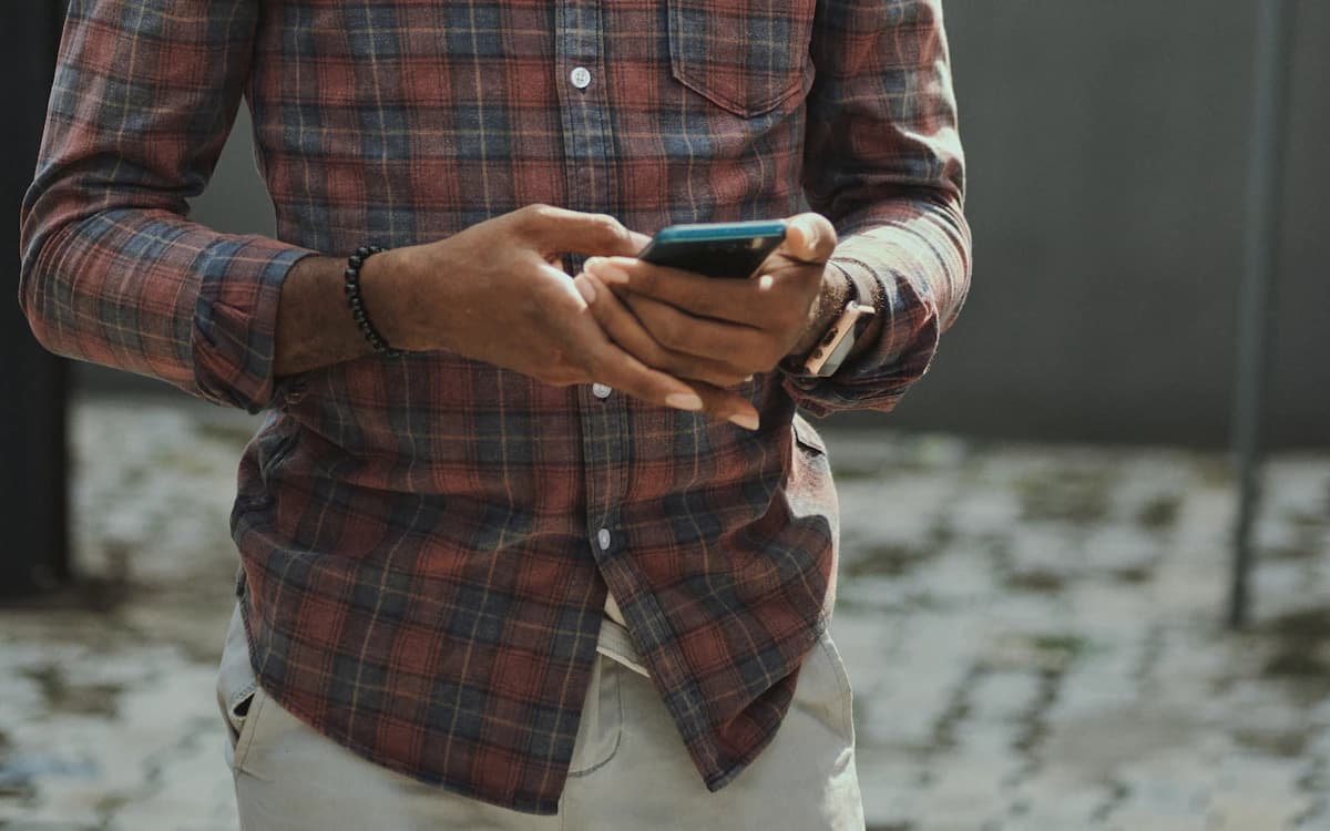 A tradesperson in a plaid work shirt looking at a smartphone on a job site